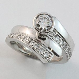 Diamond set band with a rubbed-in brilliant cut diamond termination. An interlocking wedding band completes the picture.